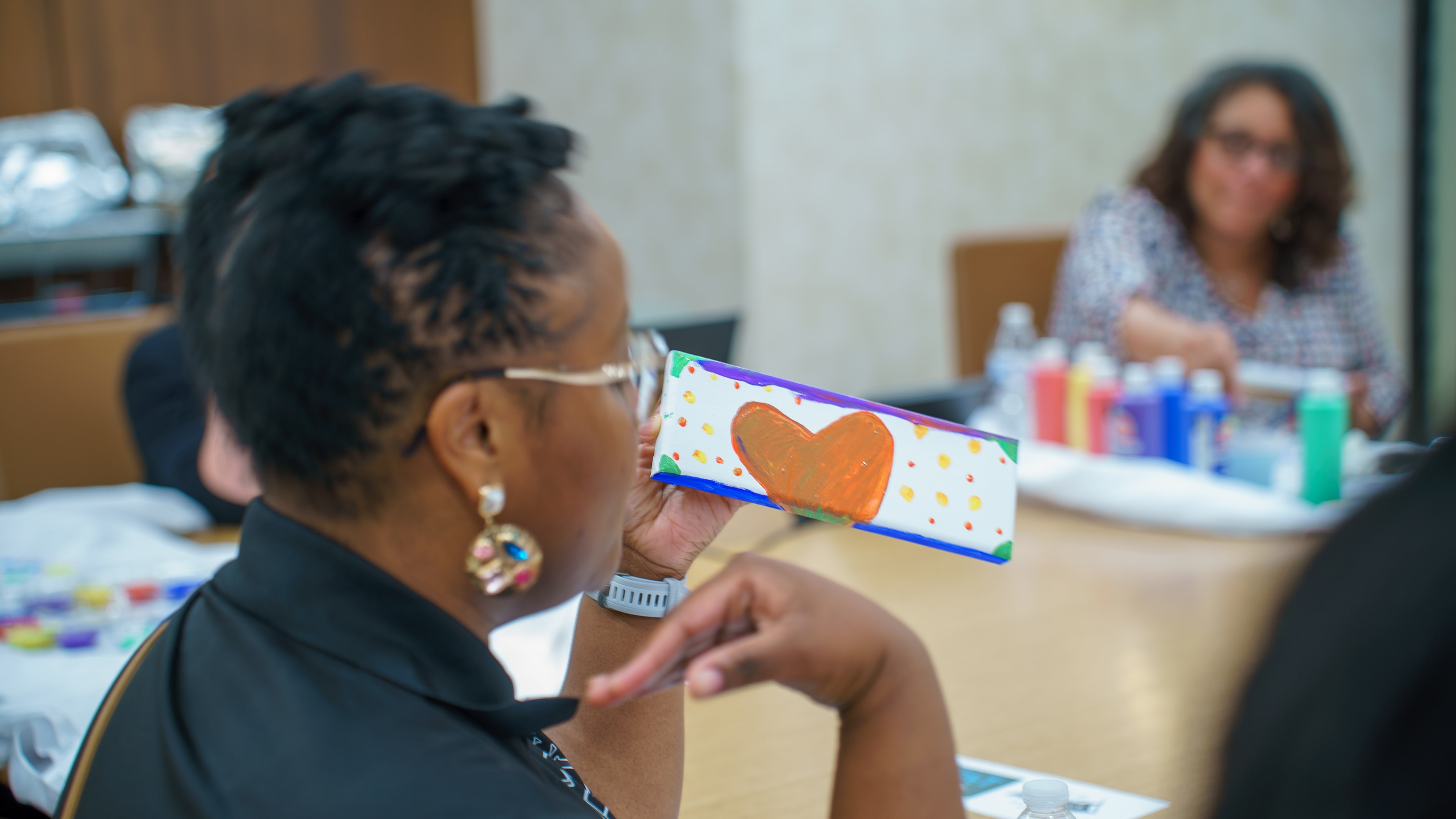 Attendee holding a painted heart canvas at Friday Morning Fundraising